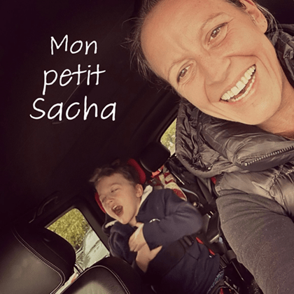 Photo de l'intérieur d'une voiture : une mère à l'avant, au premier plan et son enfant polyhandicapé à l'arrière rient aux éclats avec pour titre 